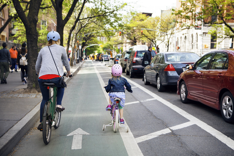 Rückansicht von Mutter und Tochter beim Fahrradfahren in der Stadt, lizenzfreies Stockfoto