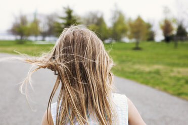 Rear view of girl on road amidst field - CAVF15980