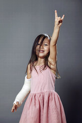 Porträt eines Mädchens mit Handzeichen vor grauem Hintergrund - CAVF15985