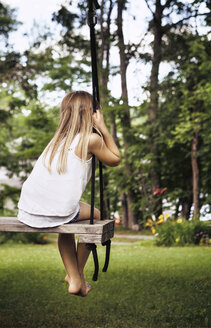 Rückansicht eines Mädchens, das auf einer Schaukel im Park sitzt - CAVF15998