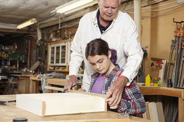 Schreiner hilft Mädchen bei der Herstellung eines Holzregals - CAVF16017