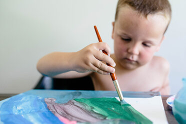 Hemdloser Junge malt auf Papier, während er zu Hause am Tisch sitzt - CAVF16026