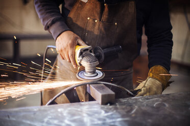 Craftsperson using circular saw while polishing metal at factory - CAVF16065