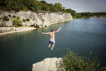 Rear view of man diving off rock into river - CAVF16076