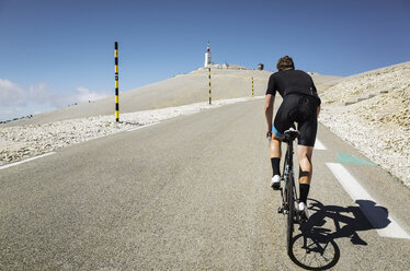 Rückansicht eines männlichen Radfahrers auf der Straße vor blauem Himmel - CAVF16093