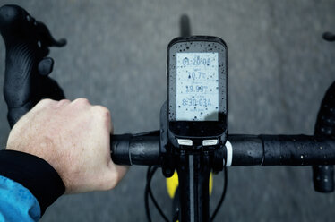 Nahaufnahme eines Mannes, der während der Regenzeit ein Fahrrad mit angeschlossenem Smartphone benutzt - CAVF16107