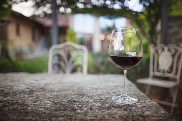 Glass of red wine on table in yard - CAVF16138