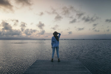 Rückansicht einer Frau, die auf einem Pier über dem Meer steht, gegen den Himmel bei Sonnenuntergang - CAVF16163