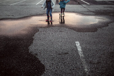 Low section of sisters playing in puddle - CAVF16197