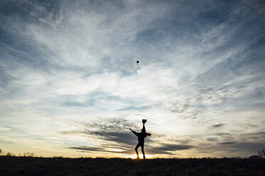 Silhouette Mädchen spielen mit Ball gegen den Himmel bei Sonnenuntergang - CAVF16198