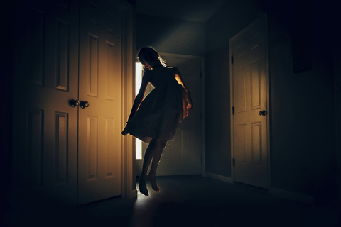 Glückliches Mädchen springt in der Dunkelkammer zu Hause, lizenzfreies Stockfoto