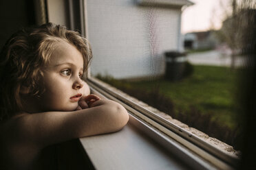 Thoughtful girl looking away while leaning on window sill - CAVF16204