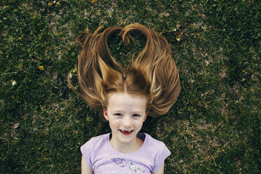 Portrait of happy girl lying on field - CAVF16206