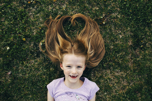 Porträt eines glücklichen Mädchens auf einer Wiese liegend - CAVF16206
