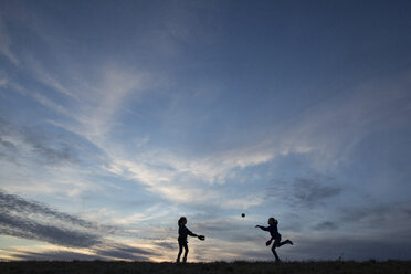 Silhouette Schwestern spielen mit Ball auf Feld gegen Himmel - CAVF16218