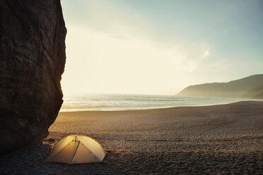 Tent by cliff on beach against clear sky during sunset - CAVF16253