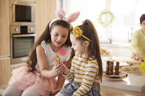 Zwei Mädchen betrachten einen Keks in der Küche, lizenzfreies Stockfoto