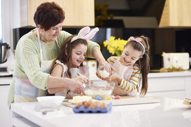 Großmutter und Enkeltöchter backen gemeinsam Osterkekse in der Küche - ABIF00180