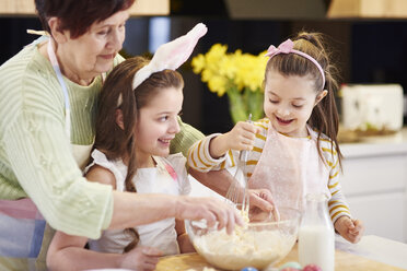 Großmutter und Enkeltöchter backen gemeinsam Osterkekse in der Küche - ABIF00181