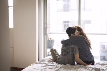 Romantische Lesben, die sich umarmen, während sie zu Hause auf dem Bett sitzen - CAVF16384