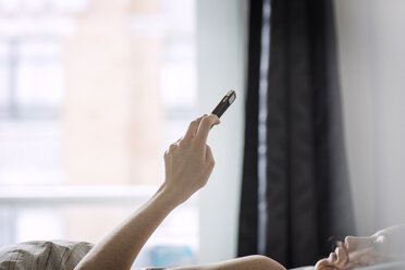 Woman using smart phone while lying on bed at home - CAVF16405