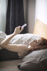 Hohe Winkel Ansicht der Frau mit Telefon während der Ruhe auf dem Bett - CAVF16406