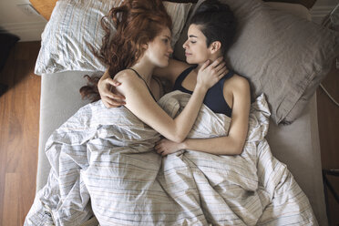 Hoher Blickwinkel auf ein romantisches lesbisches Paar, das sich gegenseitig ansieht, während es auf dem Bett liegt - CAVF16408