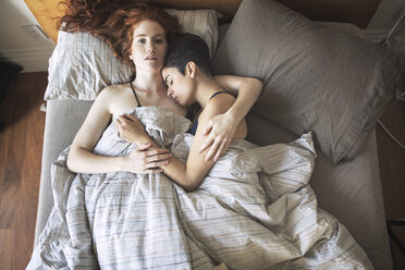 Hochwinkliges Porträt einer Lesbe mit Freundin, die sich zu Hause auf dem Bett ausruht - CAVF16413