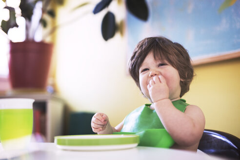 Kleiner Junge isst Essen auf einem Hochstuhl zu Hause - CAVF16449
