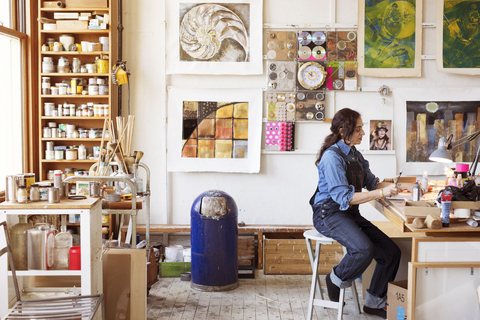 Seitenansicht eines Künstlers bei der Arbeit am Tisch im Atelier, lizenzfreies Stockfoto