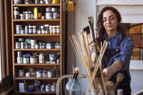 Künstlerin mit Pinseln in der Werkstatt, lizenzfreies Stockfoto