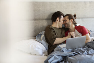 Glückliches homosexuelles Paar turtelt zu Hause auf dem Bett - CAVF16504