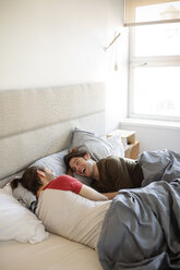 Cheerful homosexual couple relaxing on bed at home - CAVF16506