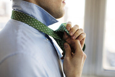 Mittelteil eines Mannes, der zu Hause eine Krawatte bindet - CAVF16522