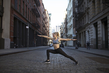 Female athlete exercising on street in city - CAVF16541