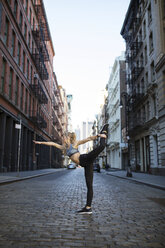 Female athlete exercising on street against sky in city - CAVF16542