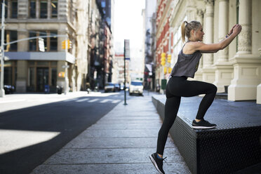 Female athlete exercising at sidewalk in city - CAVF16551