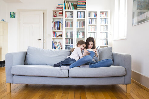 Schwestern sitzen auf der Couch und lesen ein Buch - LVF06812