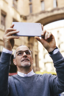 Mann beim Fotografieren mit Tablet-Computer in der Stadt - CAVF16580