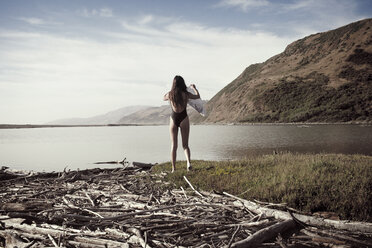 Rear view of woman wearing swimsuit while walking at seashore - CAVF16623