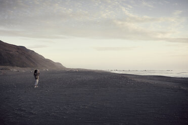 Woman standing on seashore against sky - CAVF16630