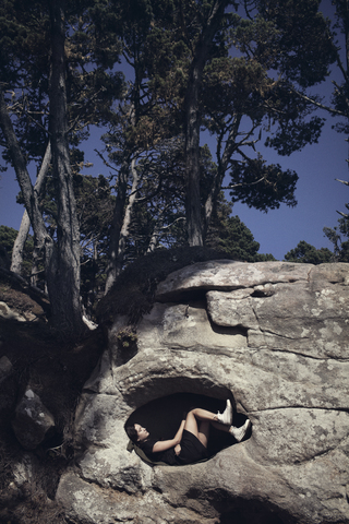 Frau im Felsen liegend gegen Bäume, lizenzfreies Stockfoto
