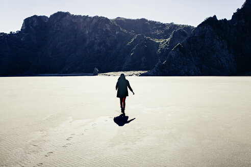 Rückansicht einer Frau, die am Bethells Beach gegen die Berge läuft - CAVF16668