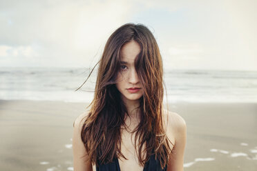 Porträt einer schönen Frau am Strand von Bethells gegen das Meer stehend - CAVF16680