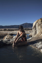 Woman sitting on rock and relaxing at Bridgeport Hot Springs - CAVF16698