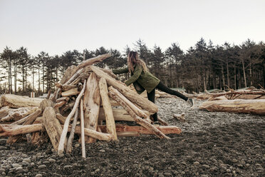 Side view of woman arranging firewood on beach during winter - CAVF16761