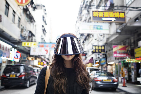 Portrait of female tourist wearing face visor on Hong Kong Street - CAVF16784