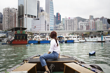 Side view of female tourist looking at buildings by sitting on boat - CAVF16786