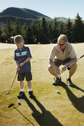 Grandfather teaching golf to boy - CAVF16842