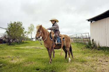 Niedlicher Cowboy reitet Pferd auf Ranch - CAVF16854